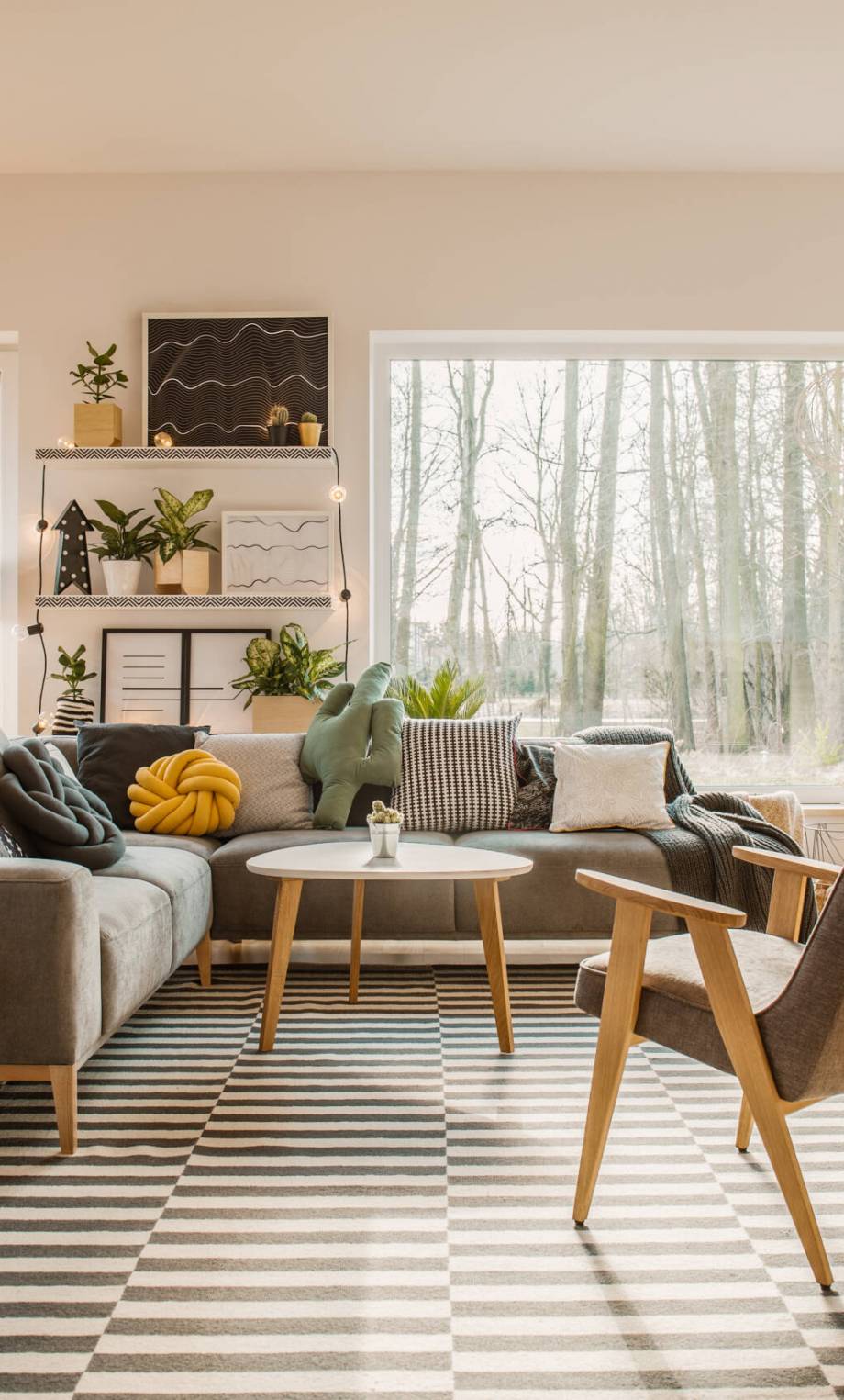 Gray, wooden furniture in a spacious living room interior with white walls and outside nature view