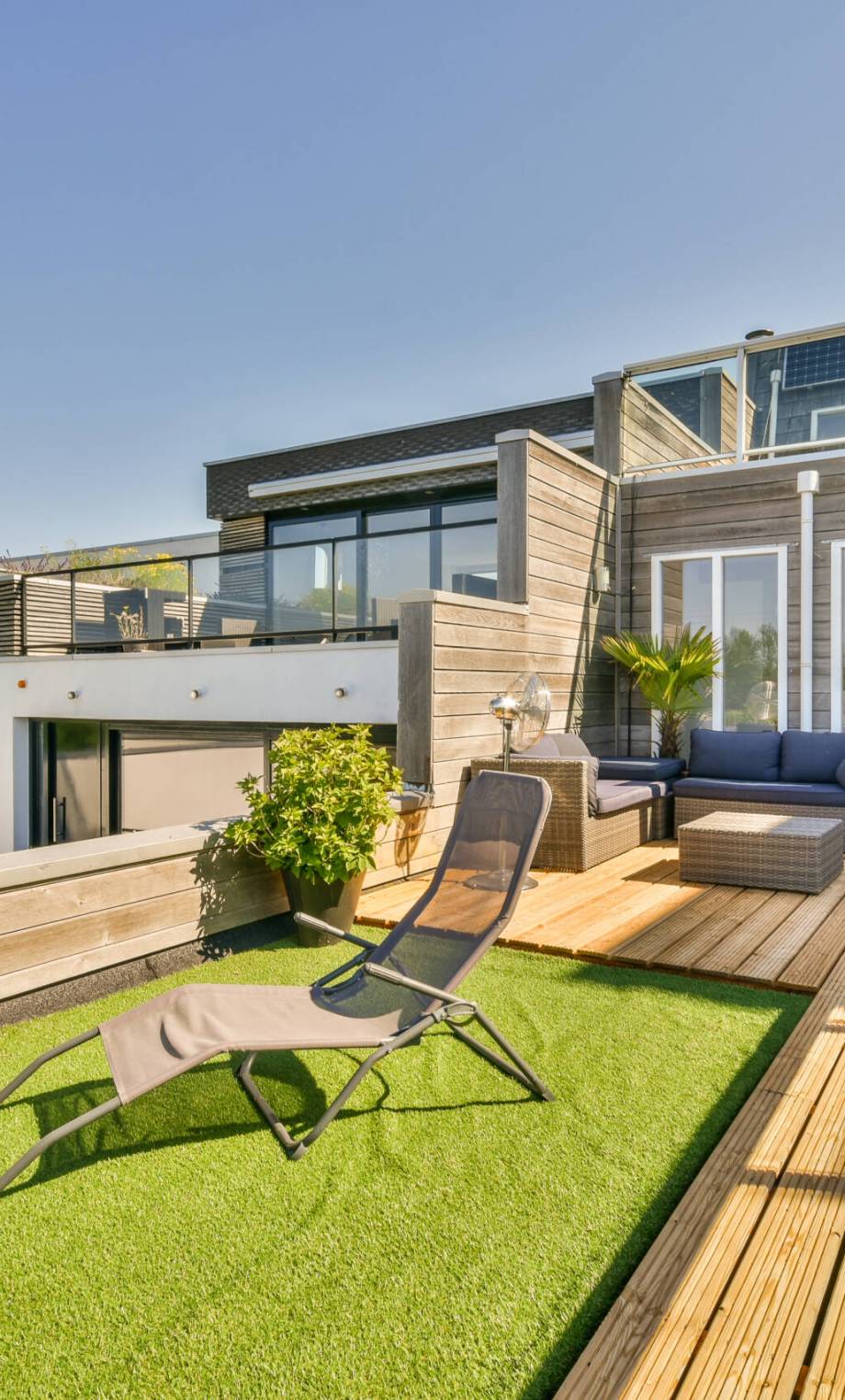 Neat paved patio with sitting area and small garden near wooden fence